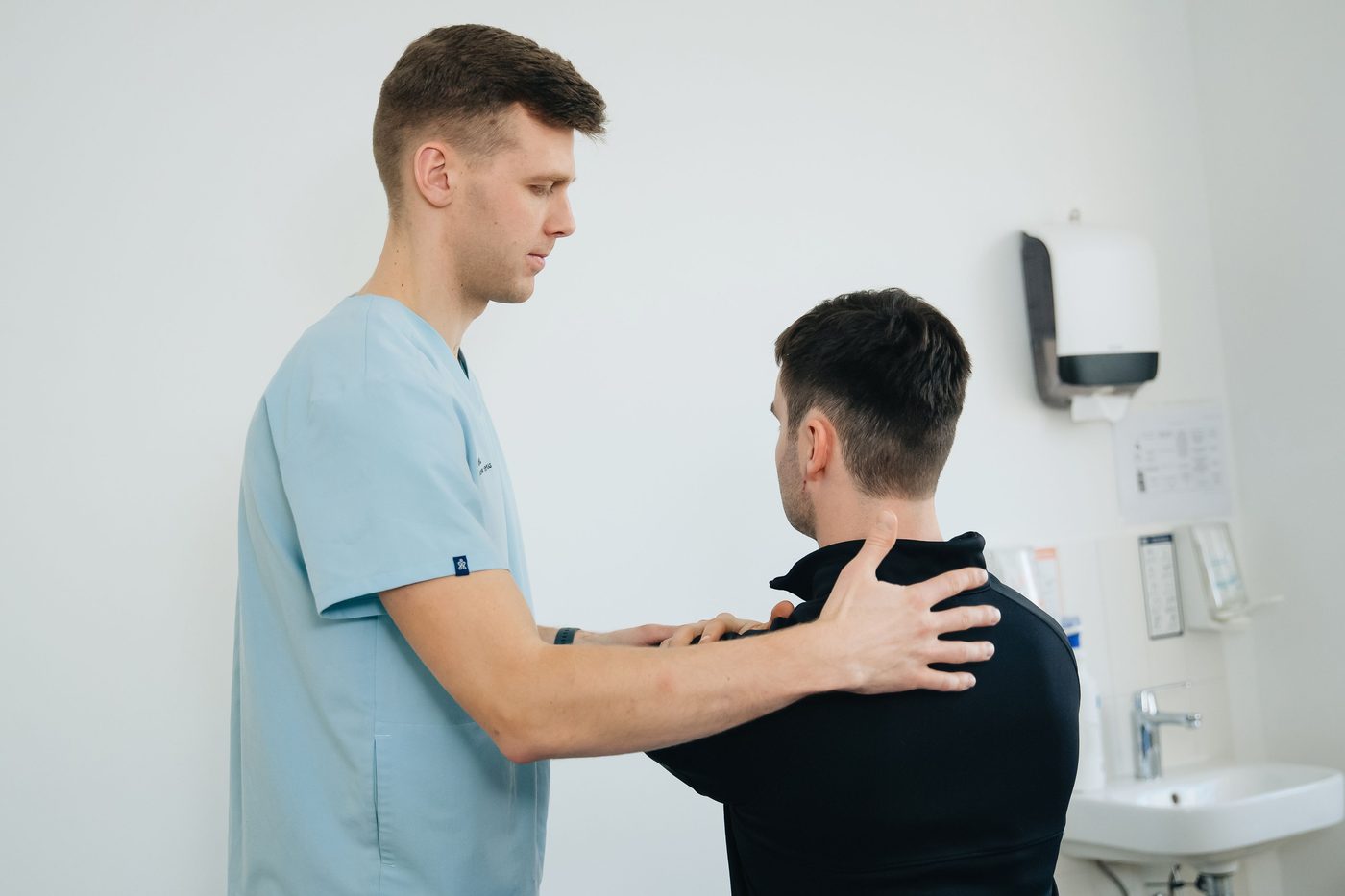 Registered massage therapist assessing a client's shoulder in a clinic
